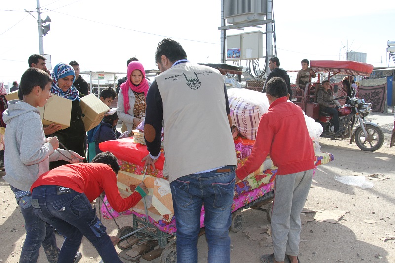 An Islamic Relief aid worker helps a family to load their winter items onto a cart in Dara Shakran camp.