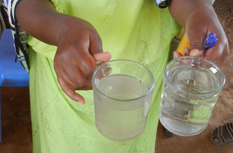 A local woman in Elkere,  Kuturi, compares unfiltered and filtered water.