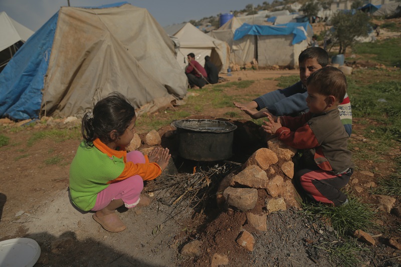 Abu Abdo's children warm themselves by the cooking fire.
