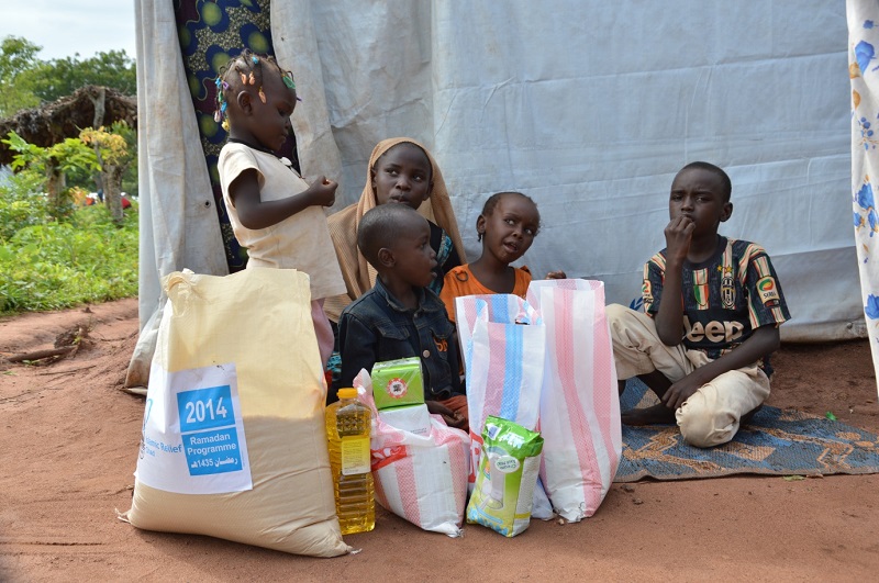 Fanne's children unpack the food parcel outside their tent.