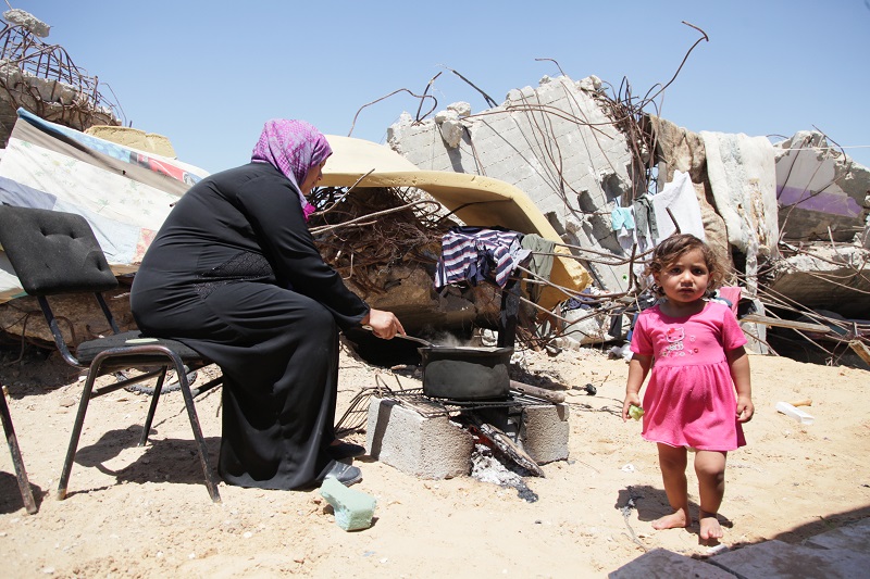 A woman cooks outside her family's makeshift shelter.