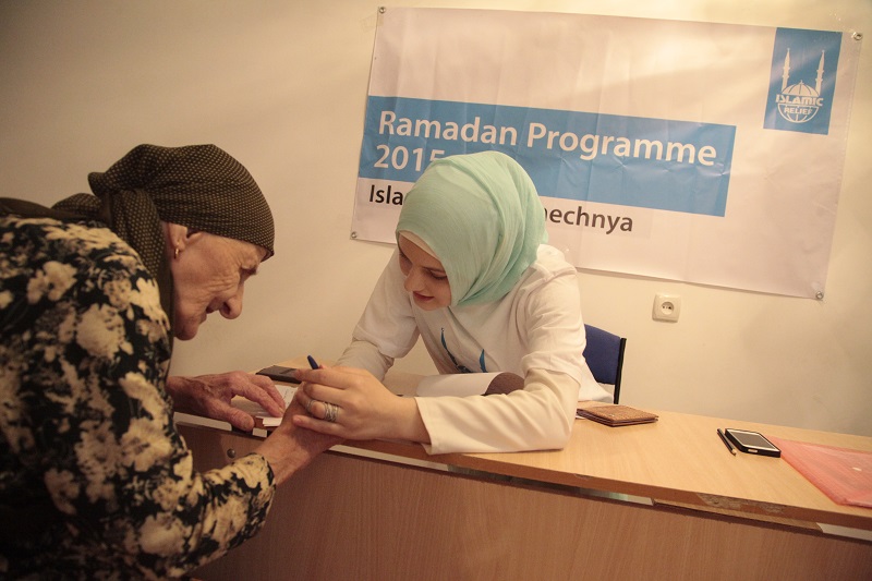 Amina helping a beneficiary sign for their Ramadan foodpack.