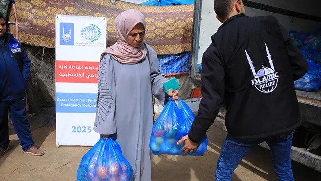 Photo: A woman receives two bags of nutritious vegetables.