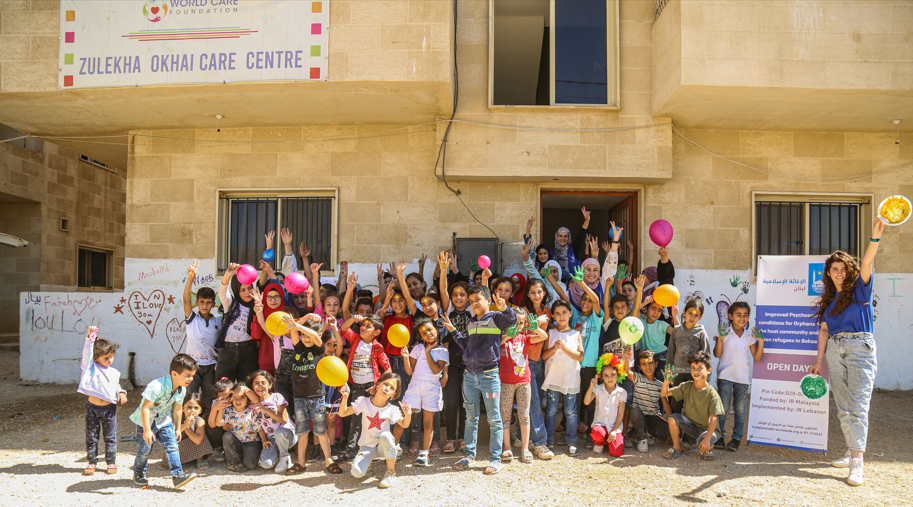 A group of children and adults pose for a photo outside a building in Lebanon